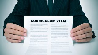a man wearing a suit showing his curriculum vitae