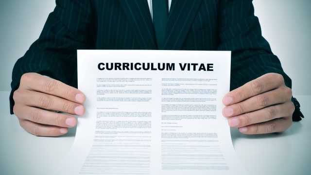 a man wearing a suit showing his curriculum vitae