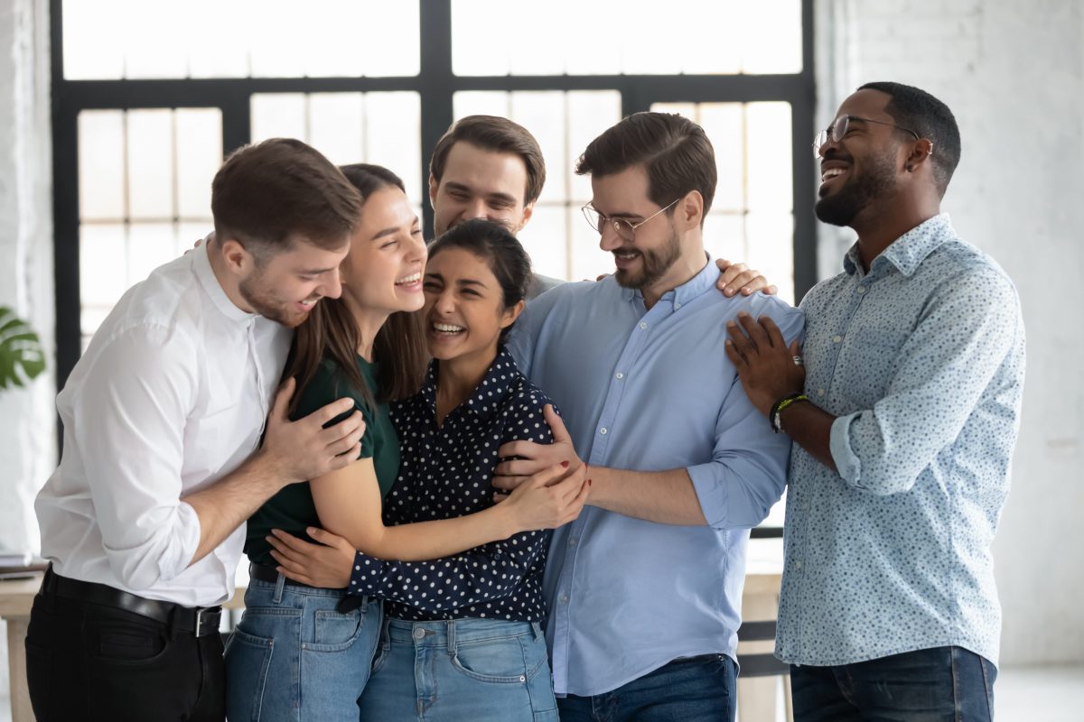 Overjoyed multiethnic friends hugging glad to see greeting each other. Corporate staff diverse members celebrating common success